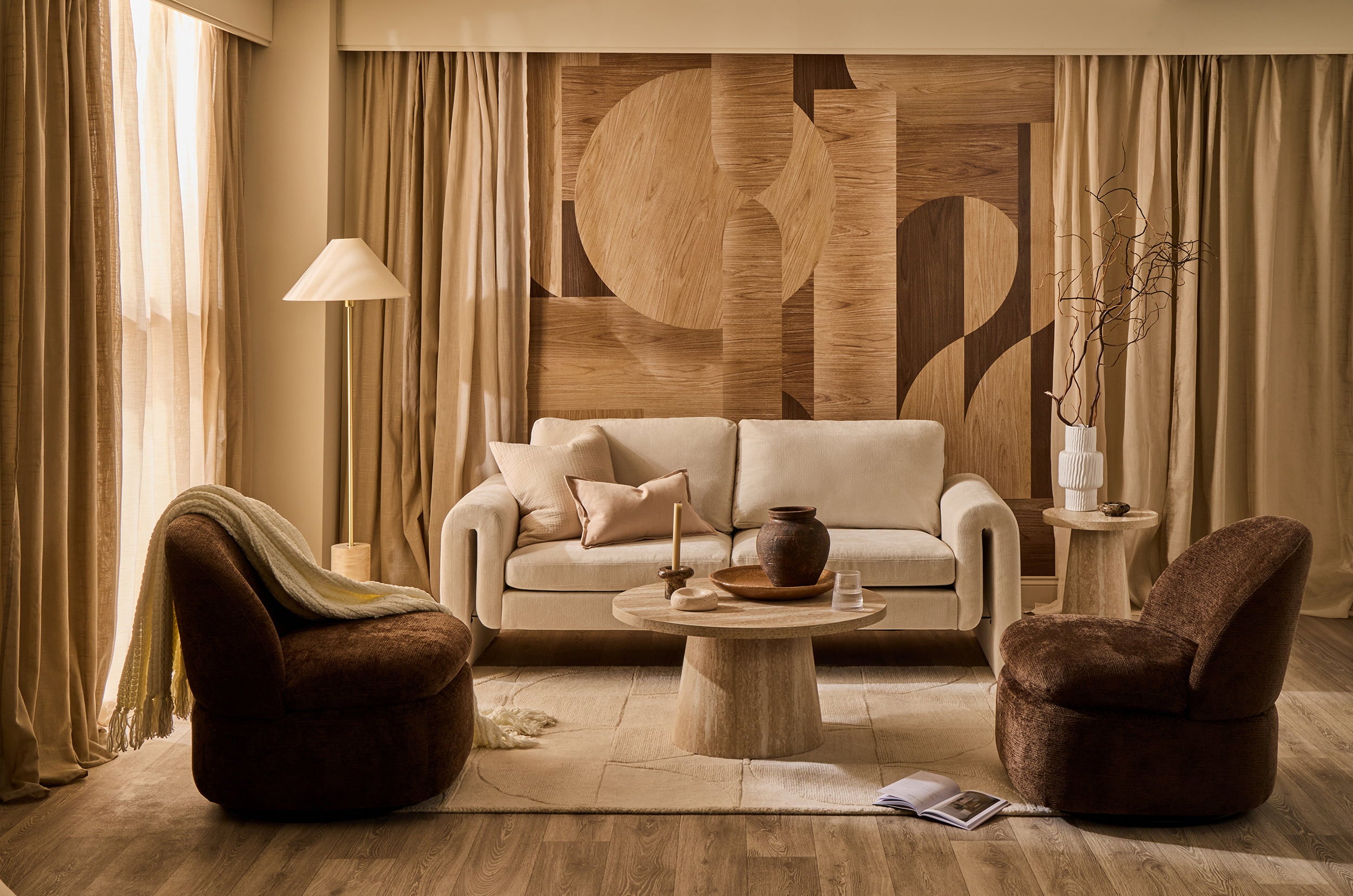 Copenhagen Calm living room with curved sofa, sculptural chairs, wooden wall panel and warm neutral tones.