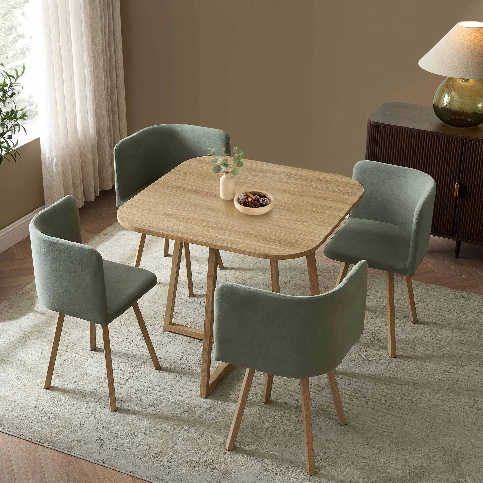 Ava 4-seater dining table and chairs in light wood with green velvet upholstery, styled in a cosy dining space.